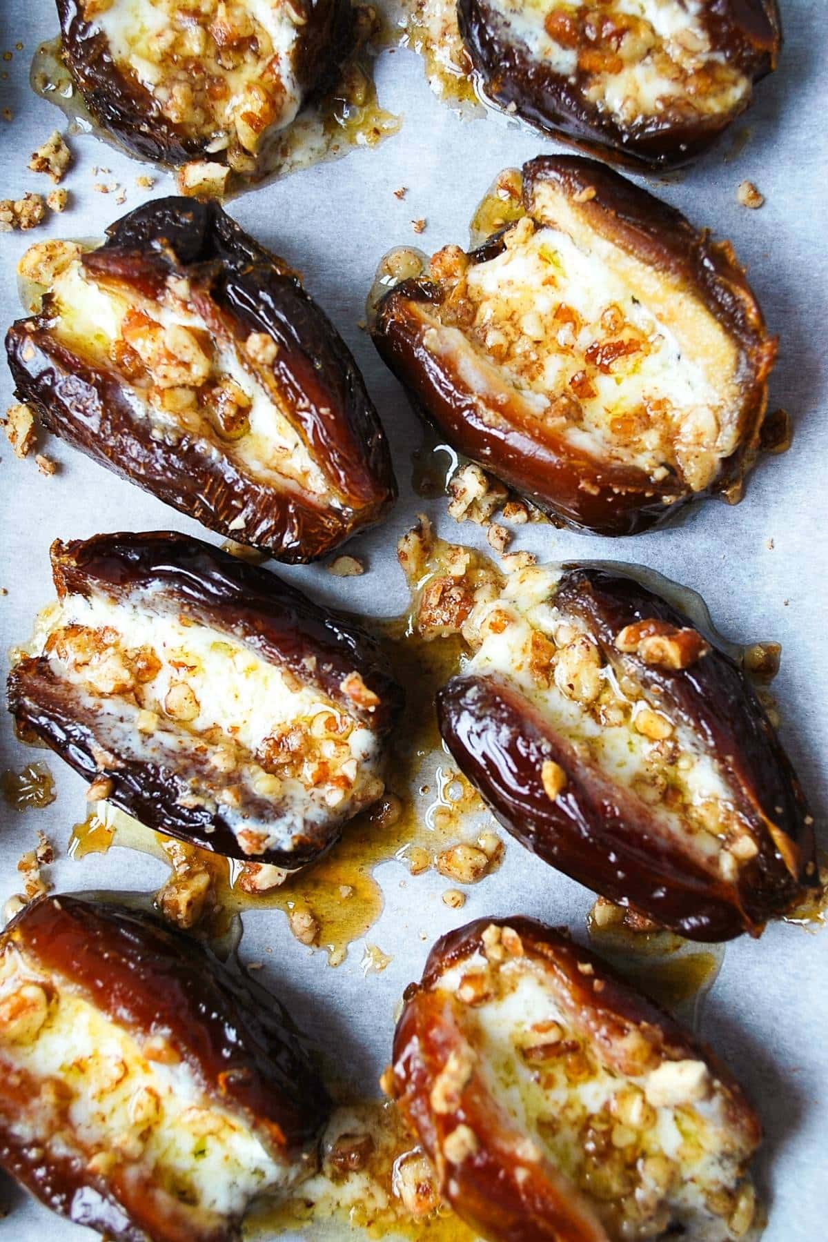 mascarpone stuffed dates with pecans and maple syrup baked on a cookie sheet with parchment paper