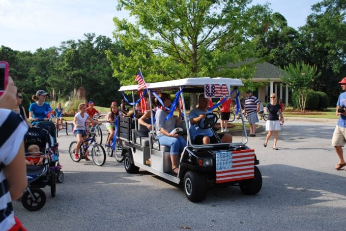 A group of people riding bikes down a street for a July 4th parade