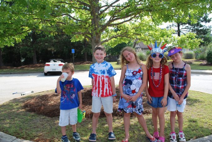 A group of young children standing next to a tree