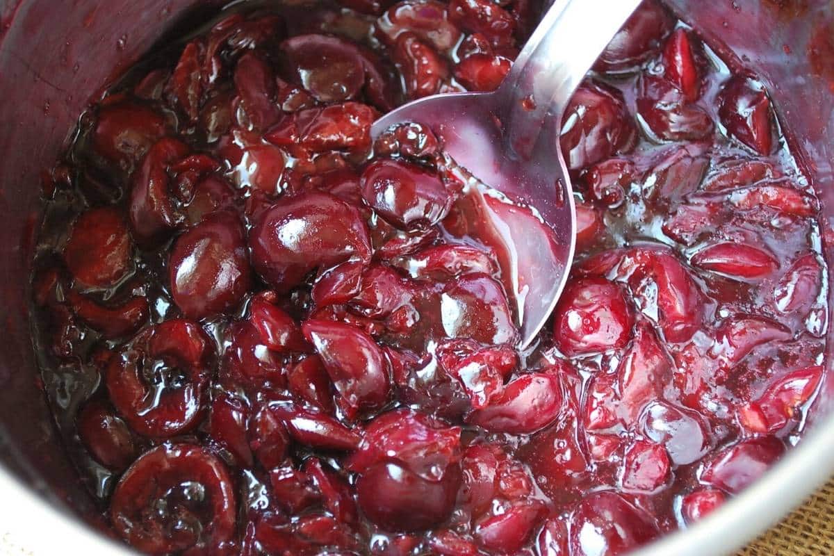 fresh cherry compote cooked in a saucepan with a spoon