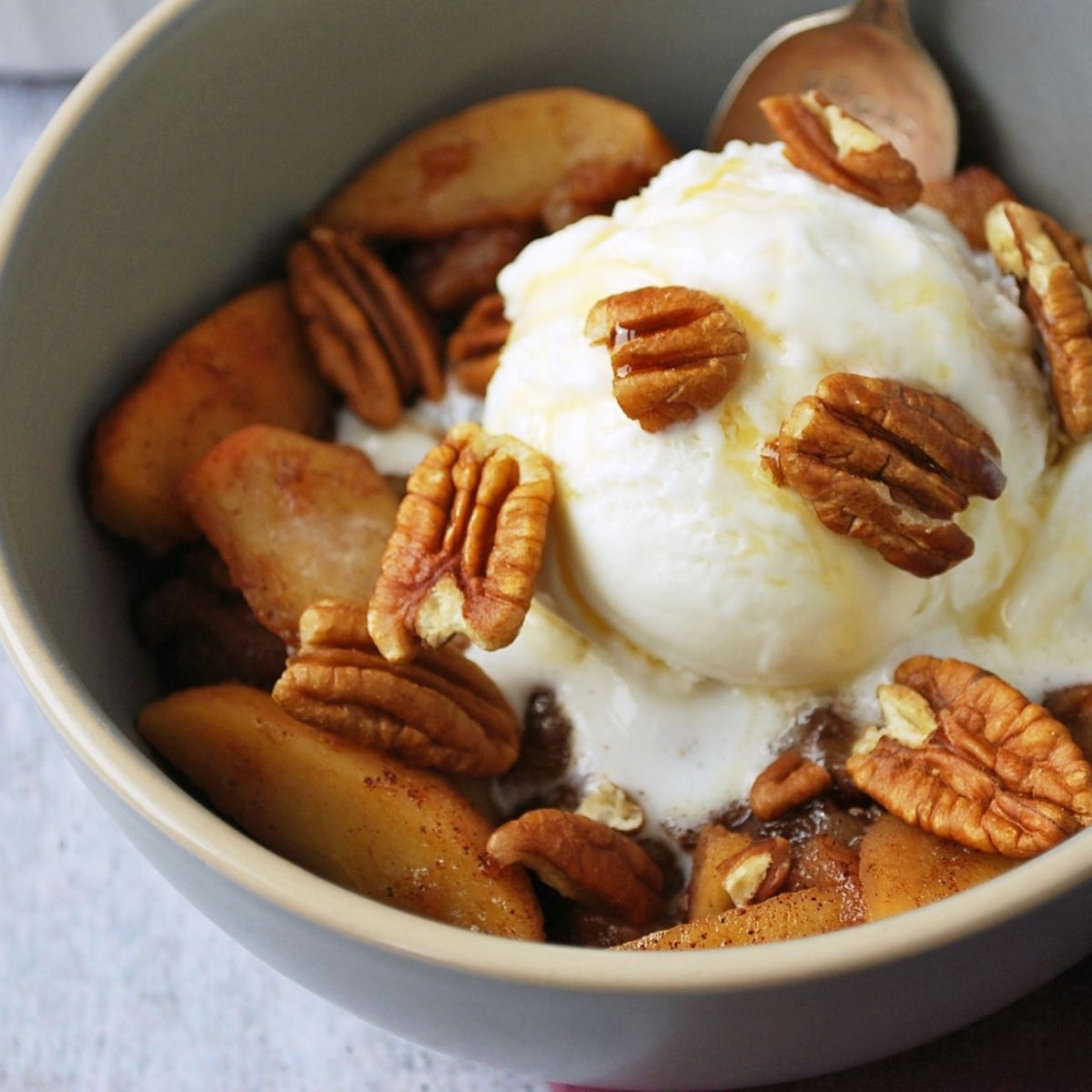cinnamon apples in a grey bowl with ice cream and a spoon