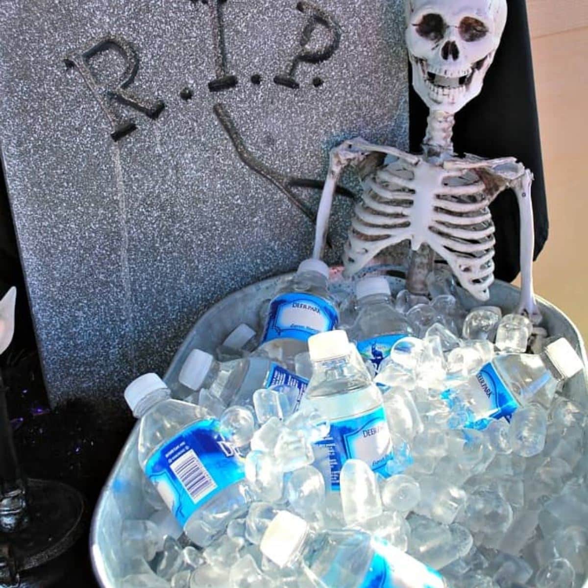 a plastic skeleton in a tub of ice with water bottles