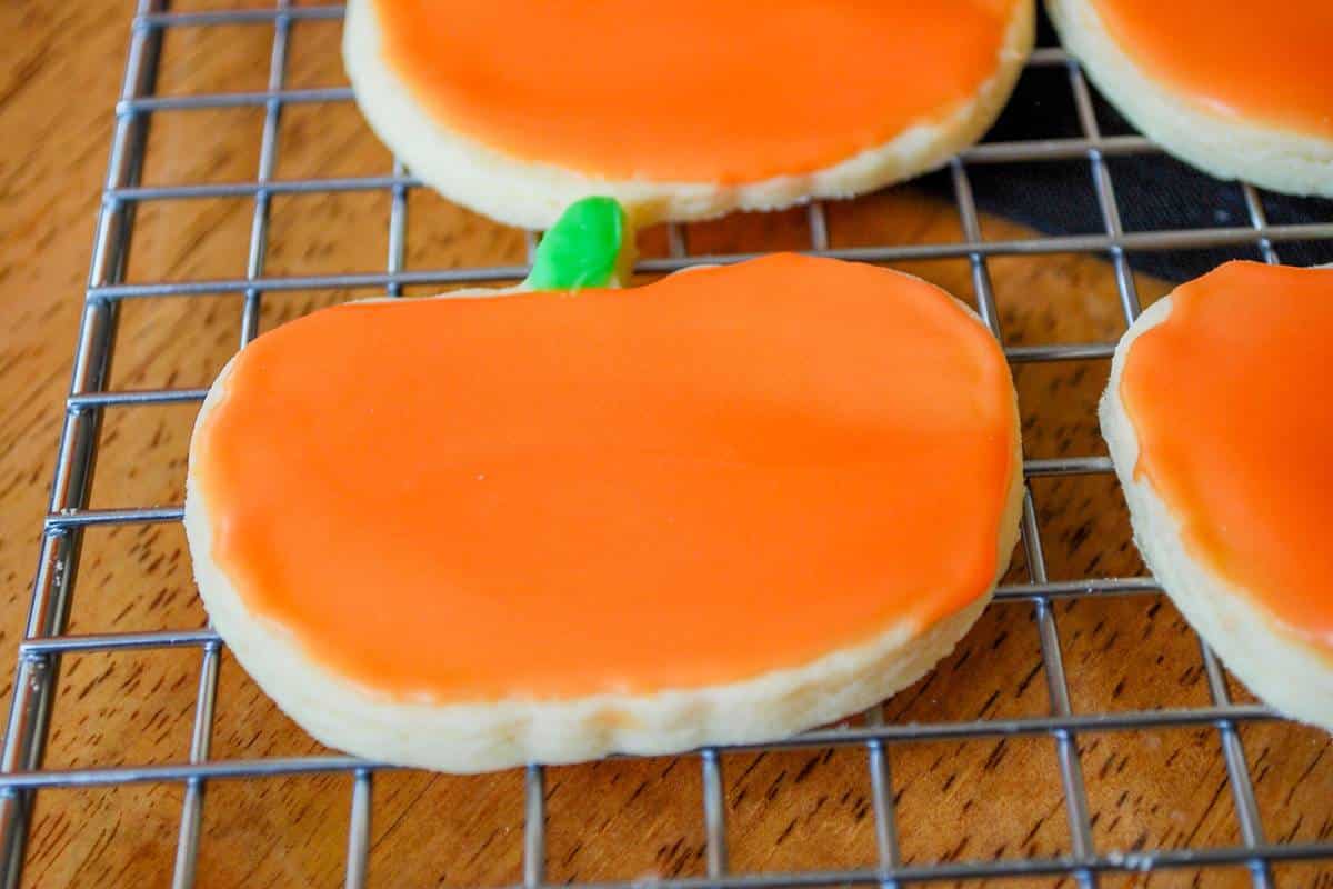a frosted pumpkin cookie on a cookie rack