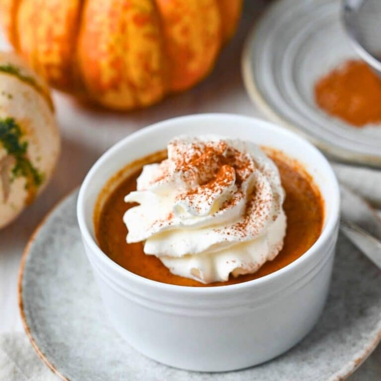a dish of custard with whipped cream and dust of cinnamon