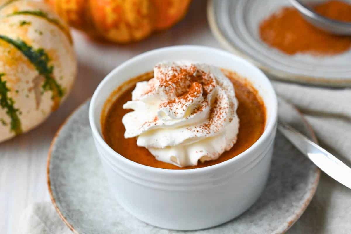 a cup of custard on a plate with a spoon