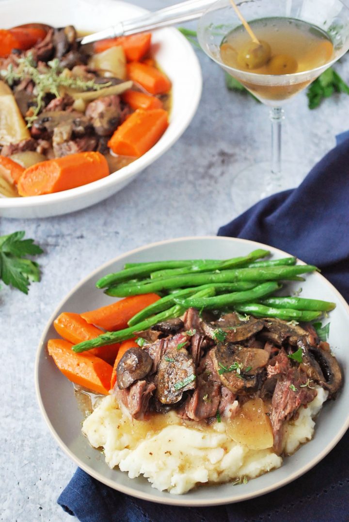 plate of roast over mashed potatoes with gravy and mushrooms