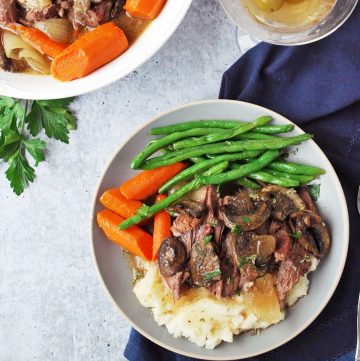 plate of beef roast with green beans and carrots and a martini with olives