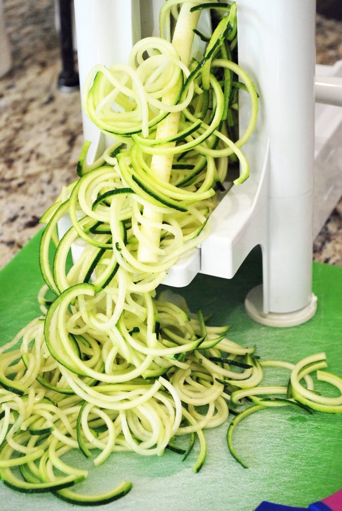 zucchini getting spiralized in a veggie spiralizer