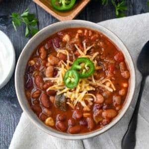 looking down at a bowl of chili with cheese and peppers