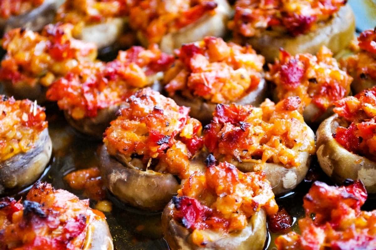 cooked mushrooms in a pan stuffed with sausage, tomatoes, and cheese