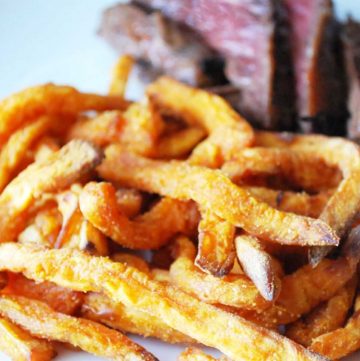 close up photo of sweet potato fries on a plate with steak