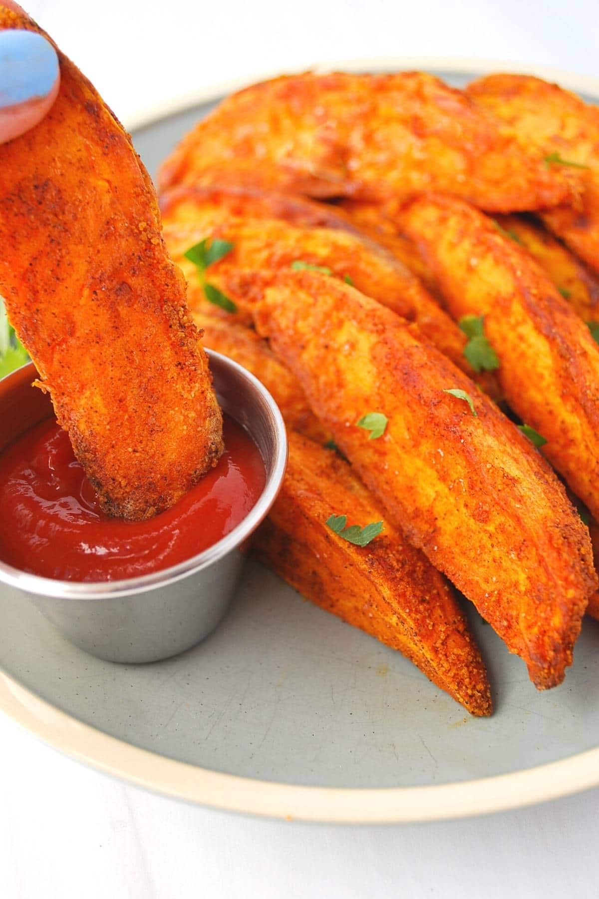 air fryer sweet potato wedge being dunked in ketchup