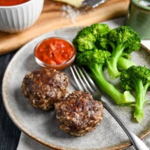 meatloaves on a plate with broccoli, marinara and a fork