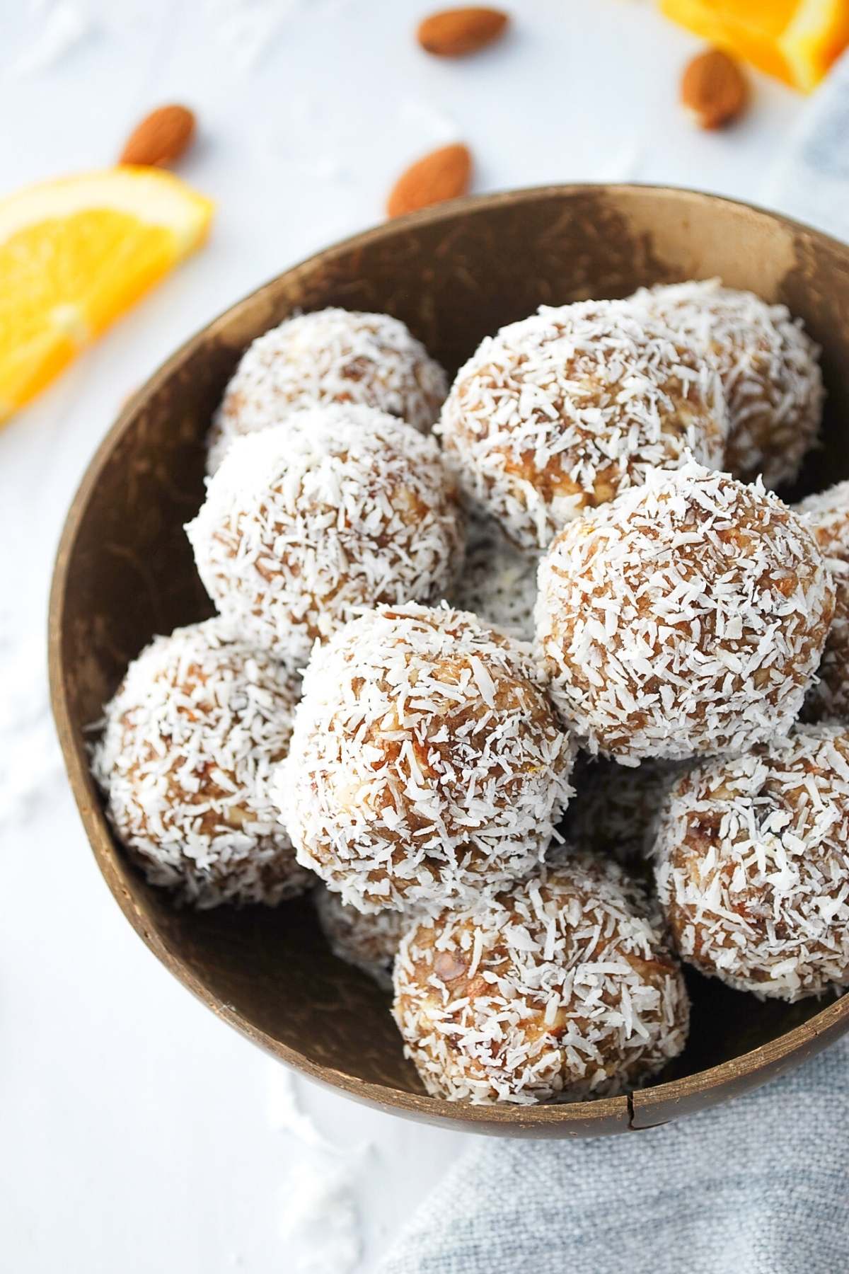 almond dates balls coated in coconut in a coconut bowl 