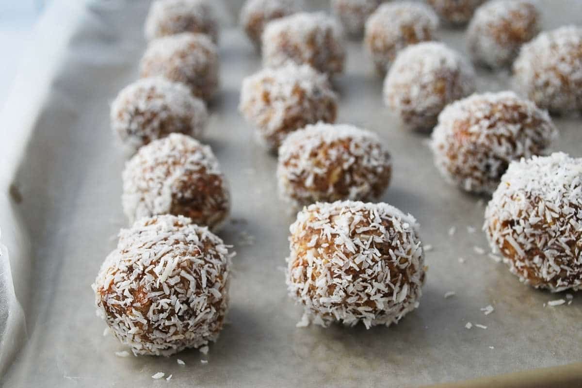 date balls covered in coconut on a wax paper lined baking sheet