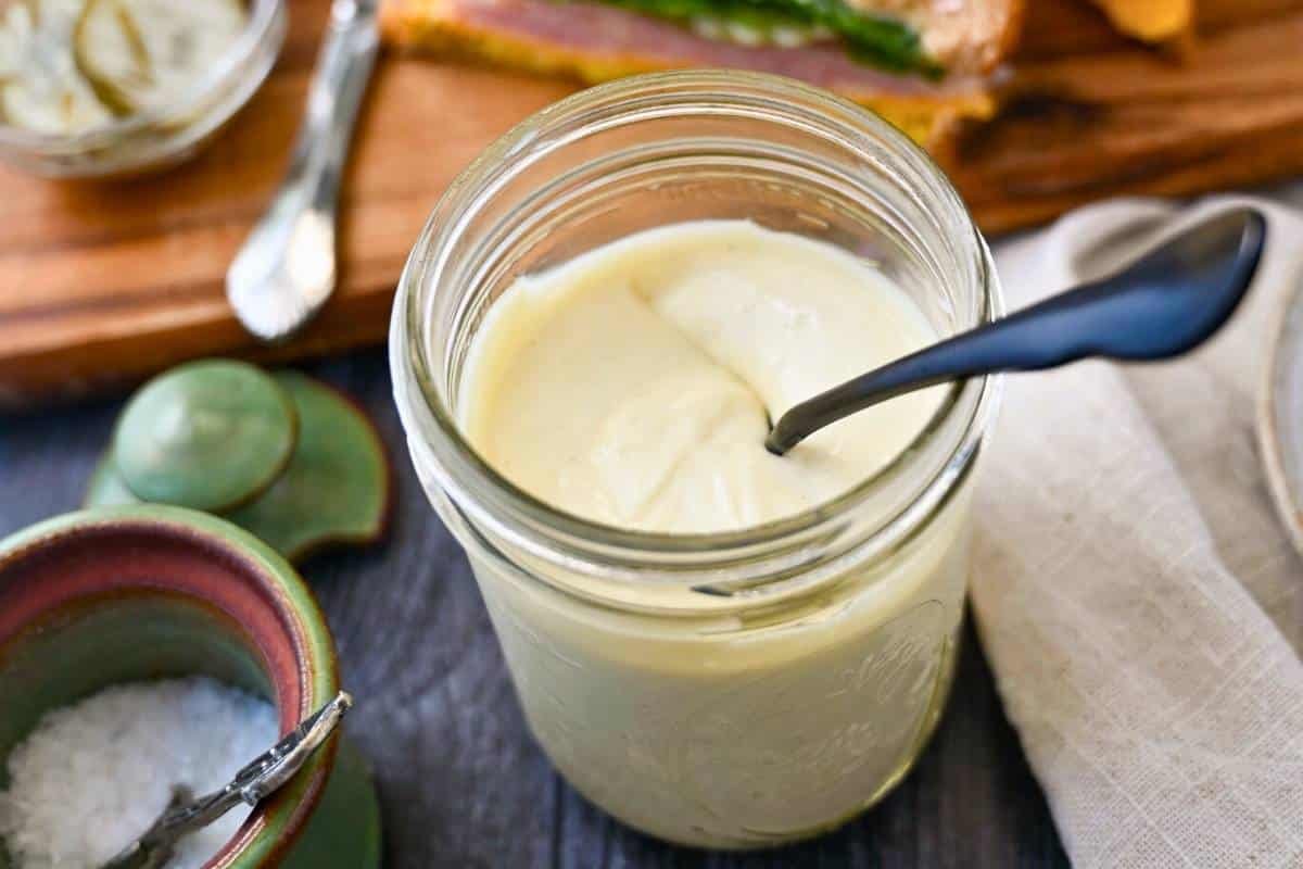 a jar of homemade avocado mayo with a jar of salt next to it