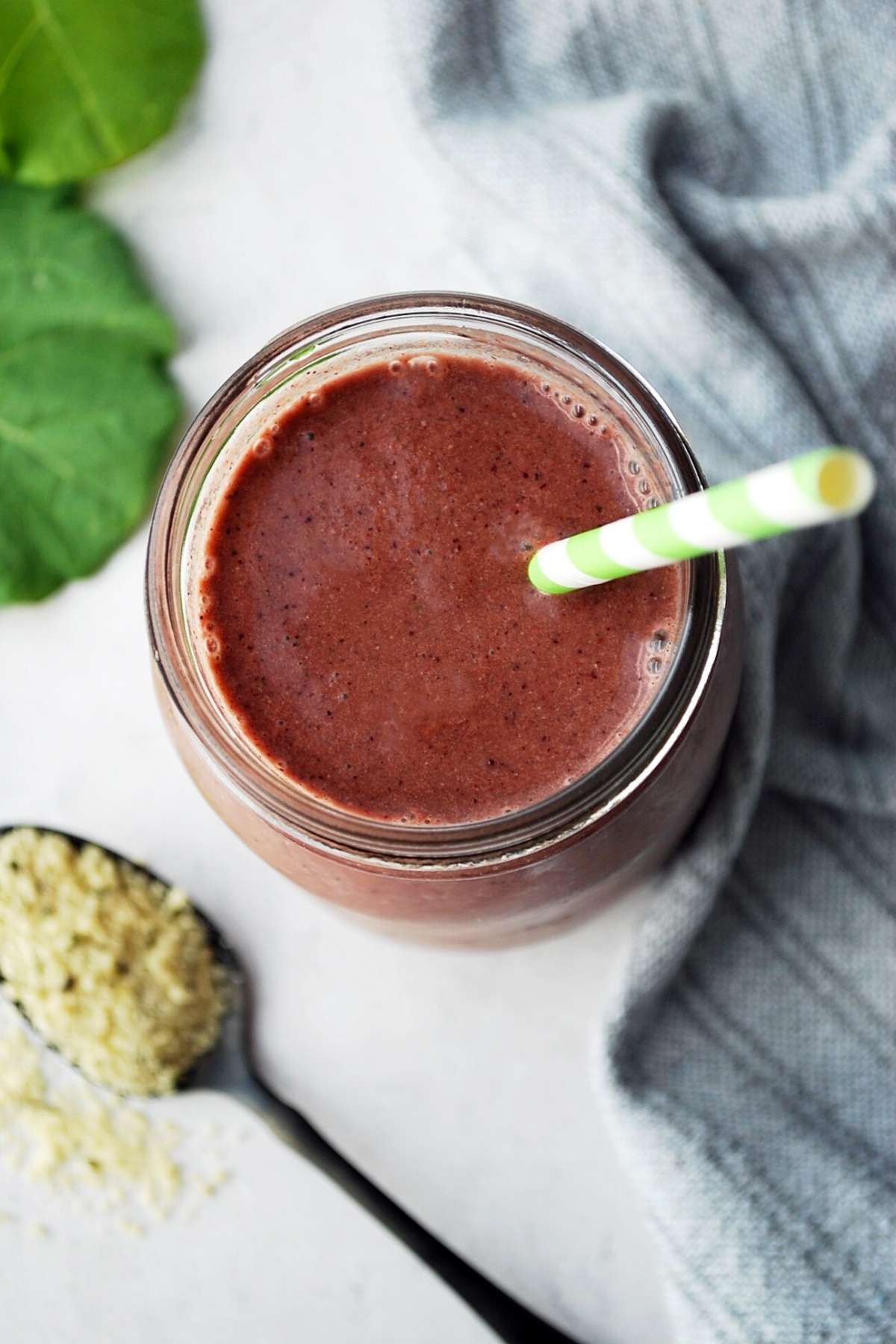 overhead shot of green smoothie in a glass with straw 