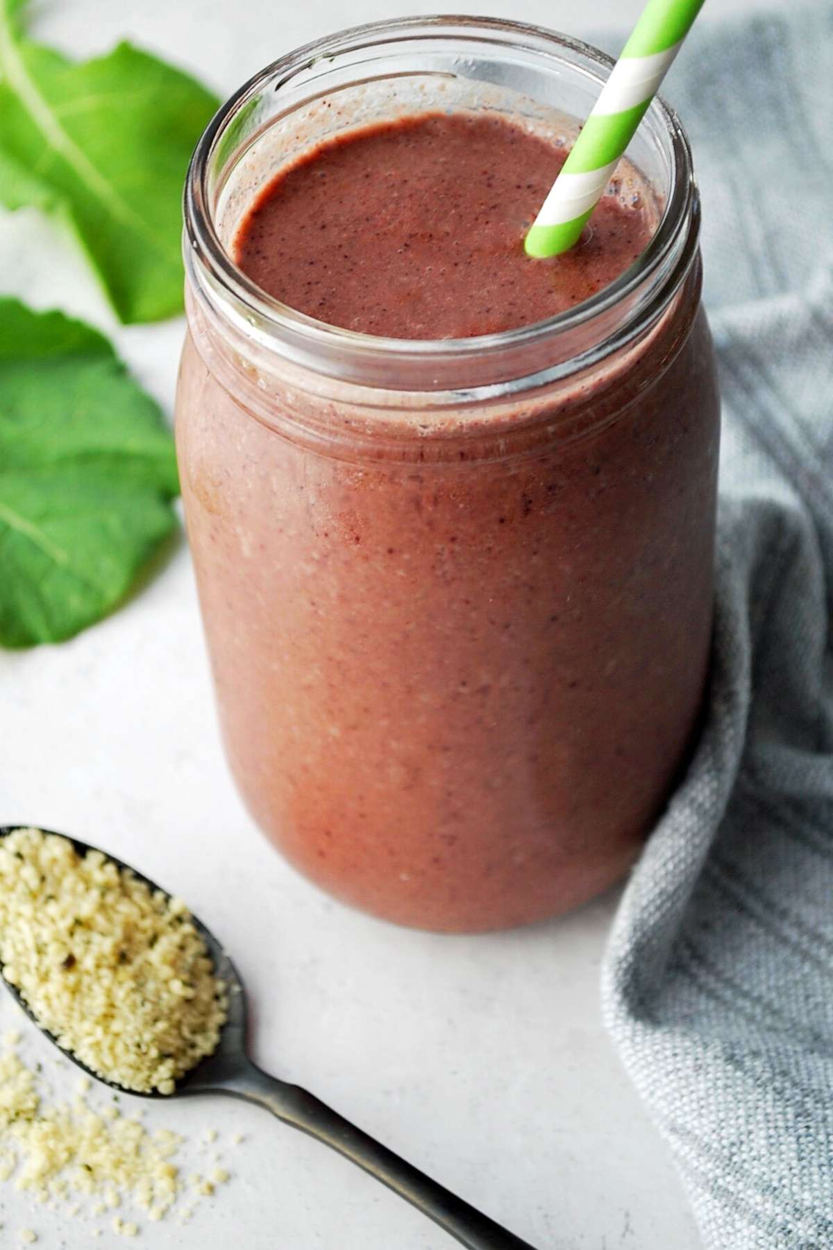 fruit and veggie smoothie in a mason jar with spoon of hemp seeds in front