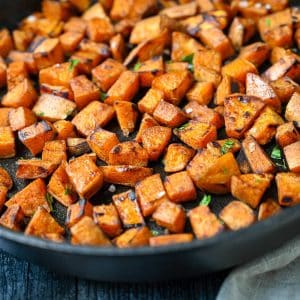 close up of cubed sweet potatoes fried in a cast iron skillet