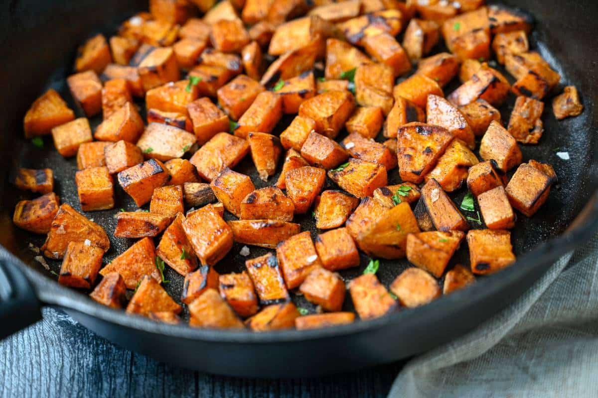 close up view of a skillet of sweet potato cubes cooked in avocado oil