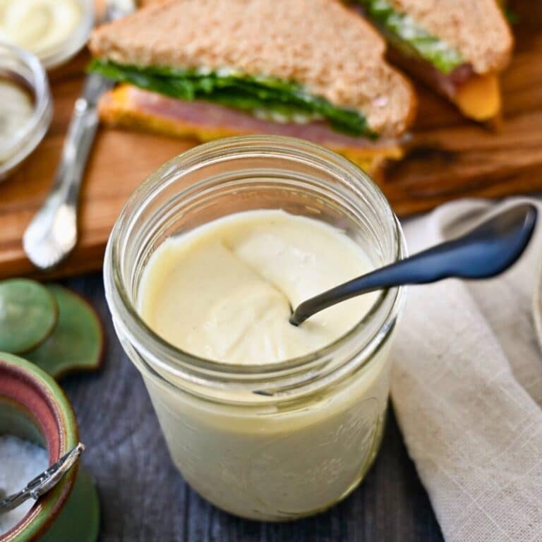 a jar of mayo with a sandwich behind it