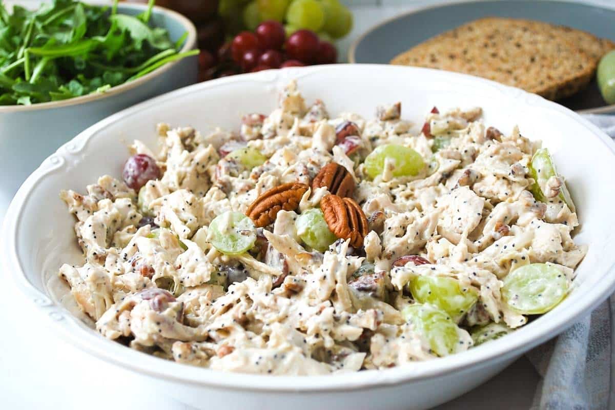 side view of a large serving bowl of chicken salad with grapes and pecans
