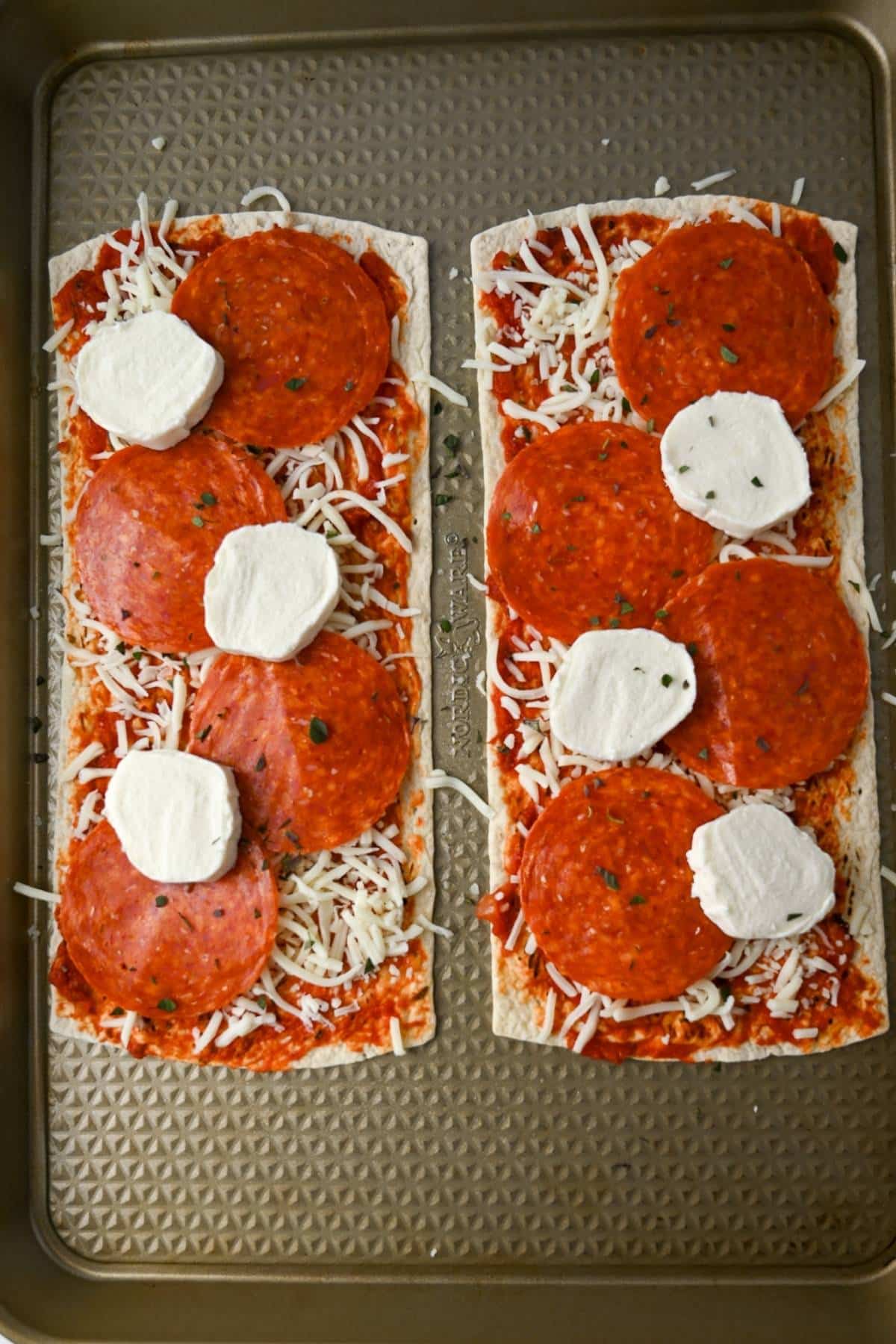 two flatbreads topped with cheese and pepperoni ready to bake