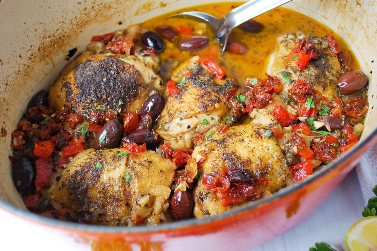 Greek chicken stew in a pot with a large serving spoon