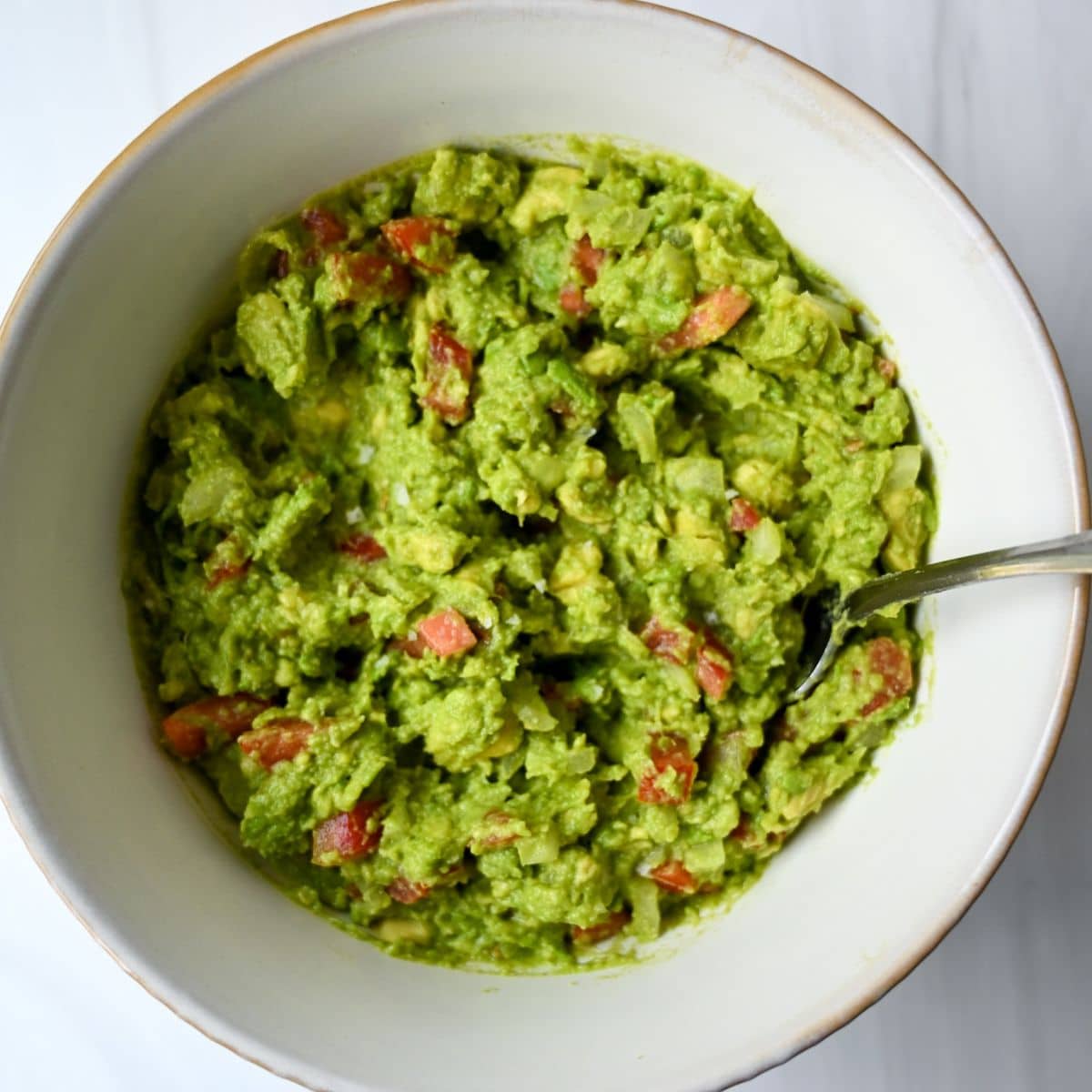 prepared guacamole in a white bowl with a fork