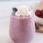 keto berry smoothie in a glass with berries on top