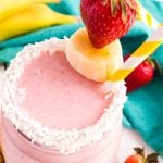 overhead photo of a strawberry smoothie with coconut on the rim and fresh fruit garnish