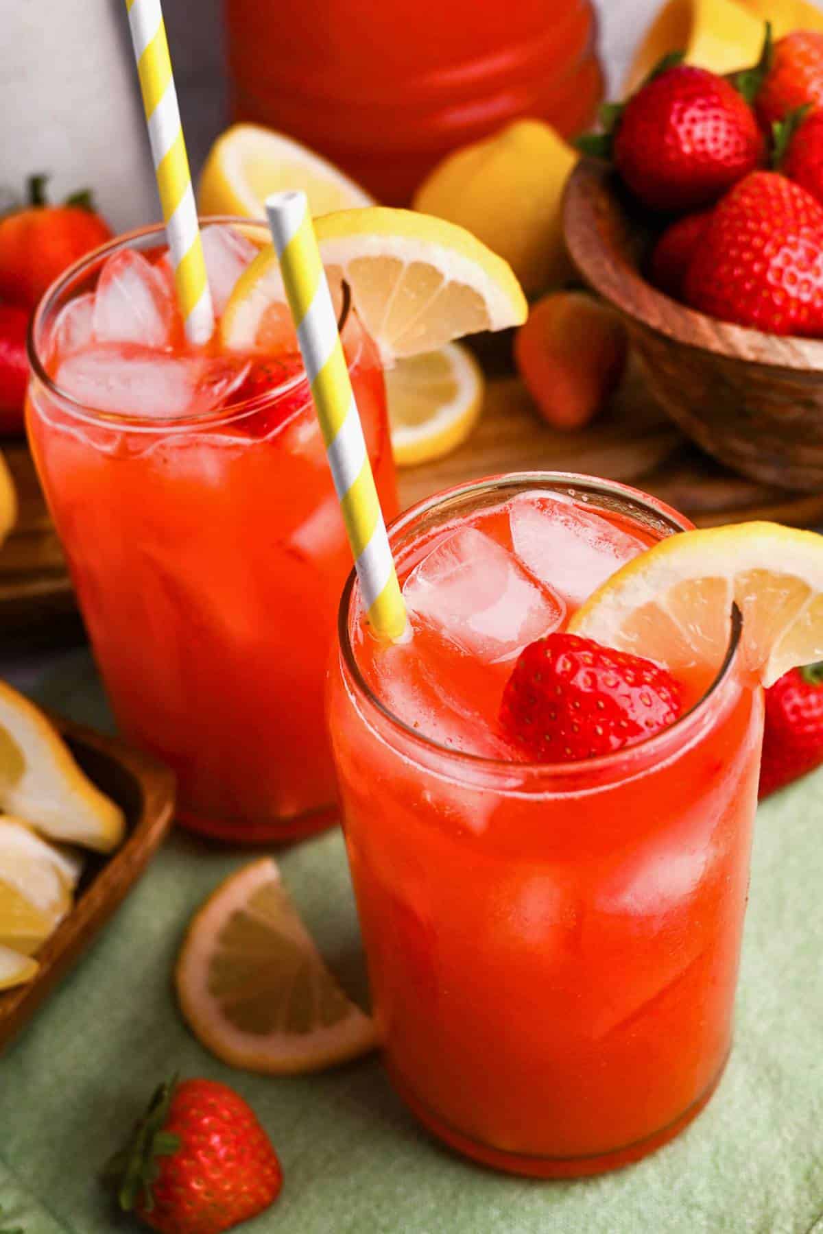 two glasses of healthier strawberry lemonade with ice and straws