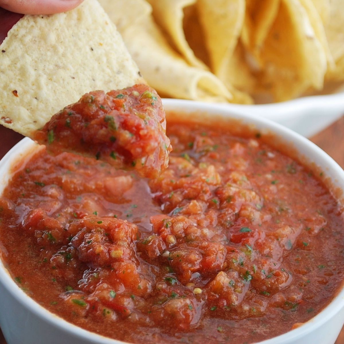 close up photo of a tortilla chip being dipped in salsa