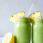 Paleo tropical green smoothies in two mason jars topped with pineapple wedges
