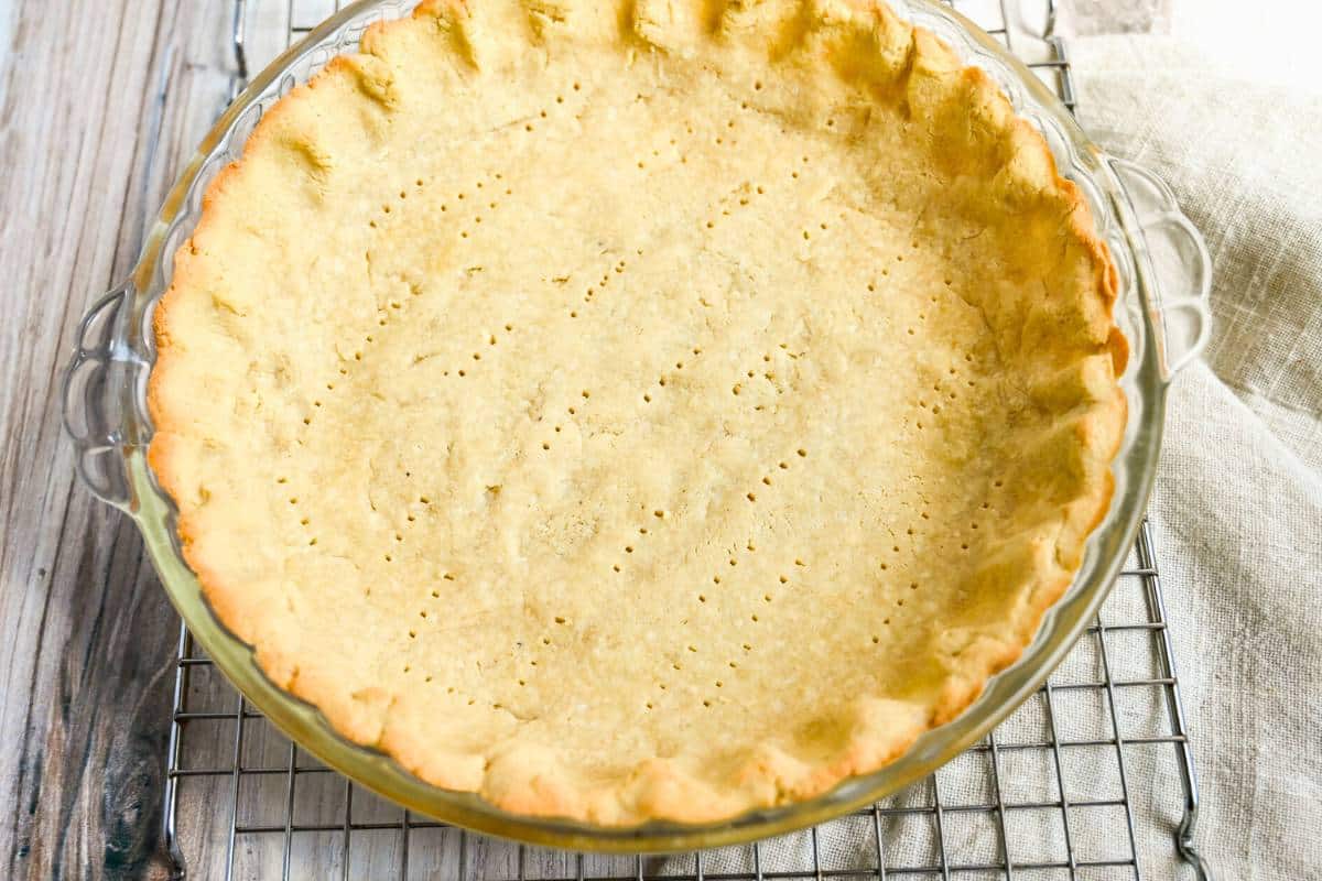 an almond pie crust on a cooling rack with a napkin under it