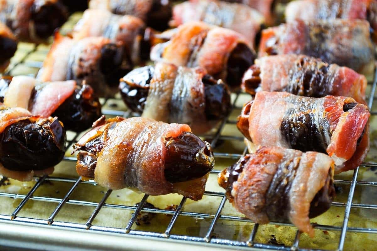 close up of bacon wrapped dates on a wire rack fresh from the oven