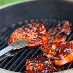 a piece of bone in bbq chicken held up with tongs