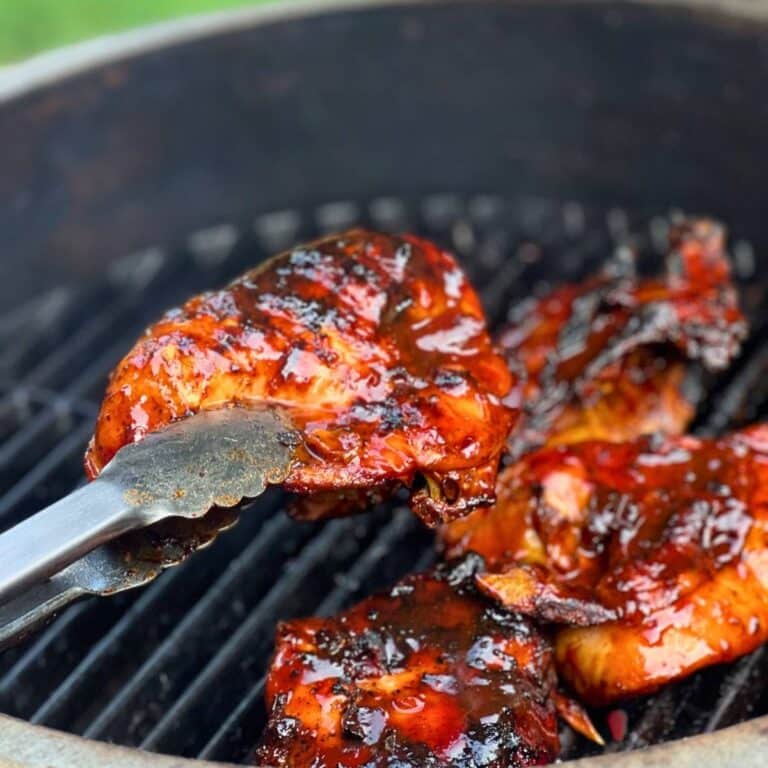 a piece of bone in bbq chicken held up with tongs
