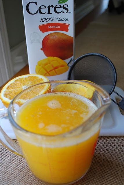 ingredients needed for orange mango popsicles with a cup of fresh squeezed orange juice
