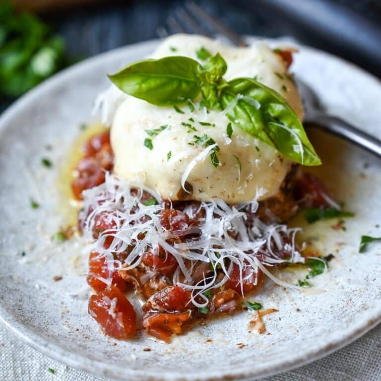 a cooked chicken breast topped with diced tomatoes, mozzarella, fresh parmesan and basil