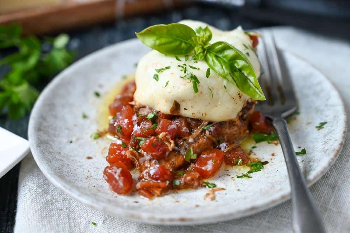 side view of caprese slow cooker chicken with fresh basil on top