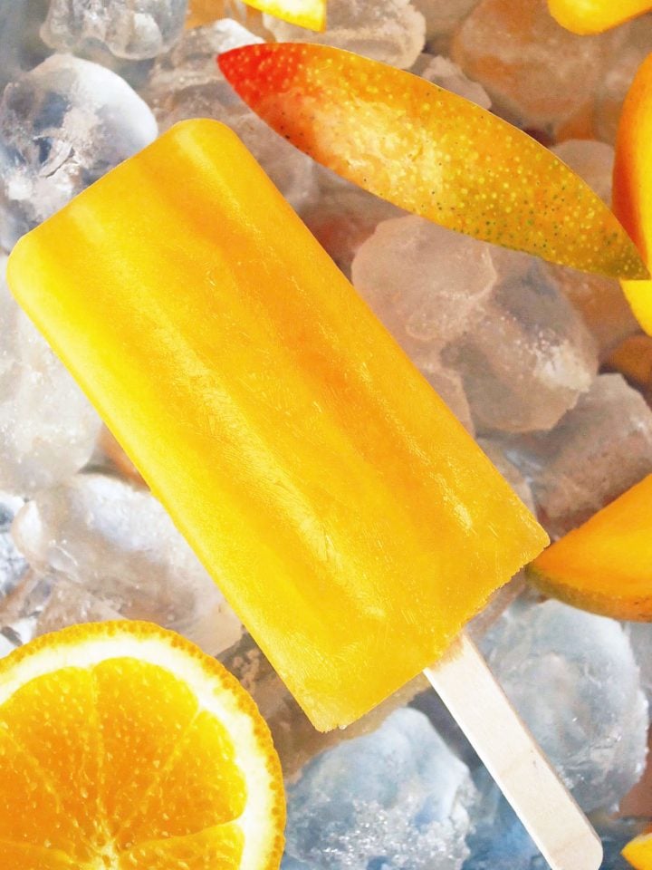 Mango orange pop on a tray of ice with sliced mango and orange