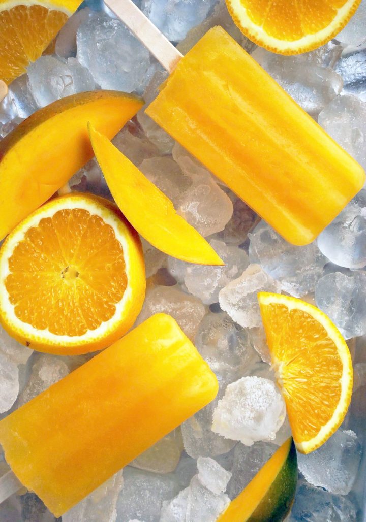 popsicles with oranges and mangos on a tray of ice