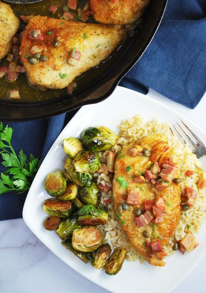 plate of chicken piccata with brussels sprouts and chicken piccata in a skillet