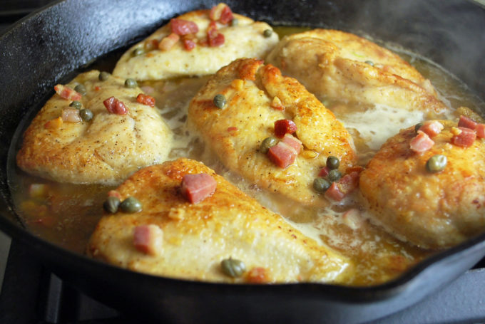 chicken piccata with capers and pancetta cooking in a skillet