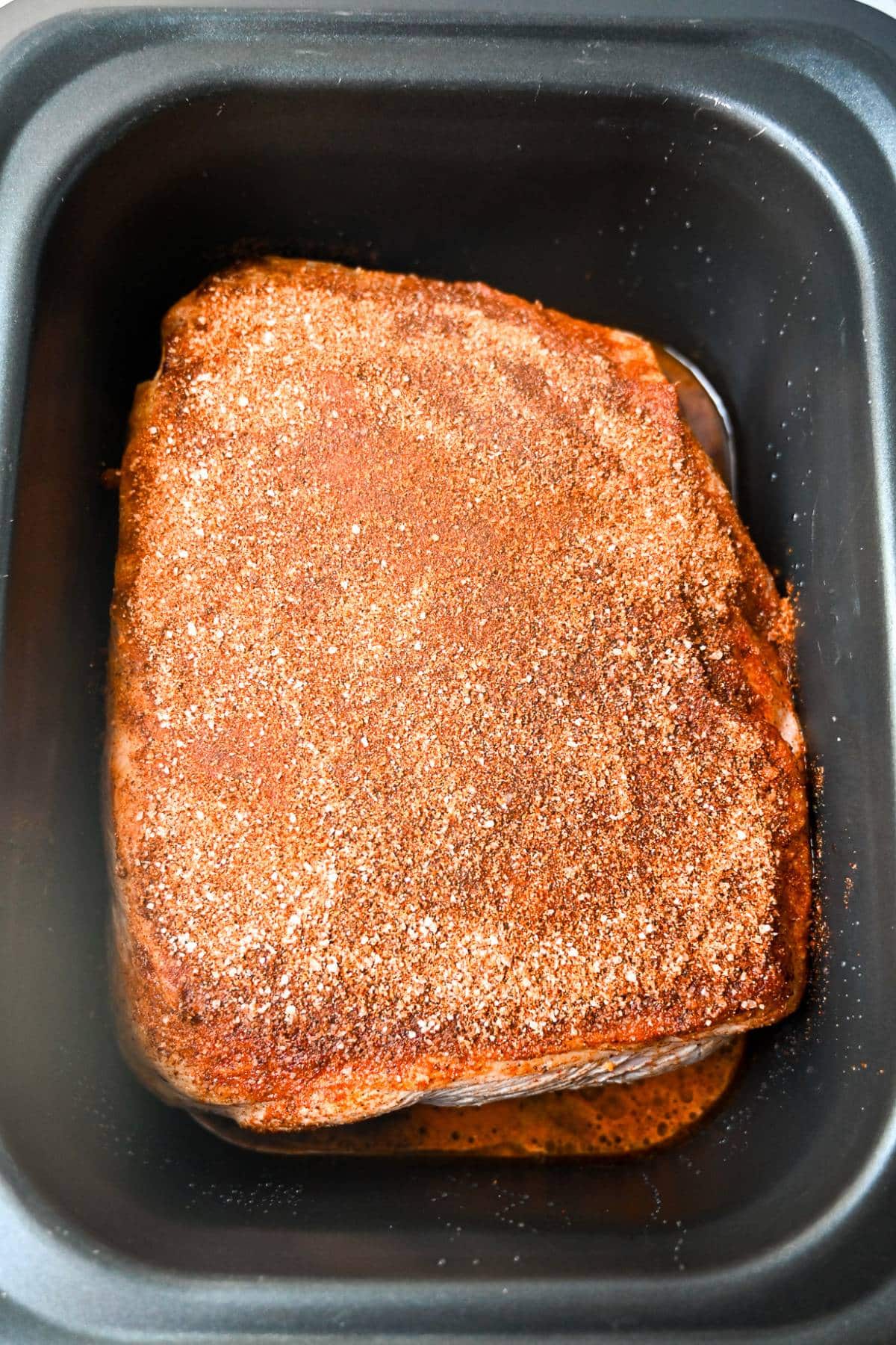 seared pork butt rubbed with spices in a slow cooker
