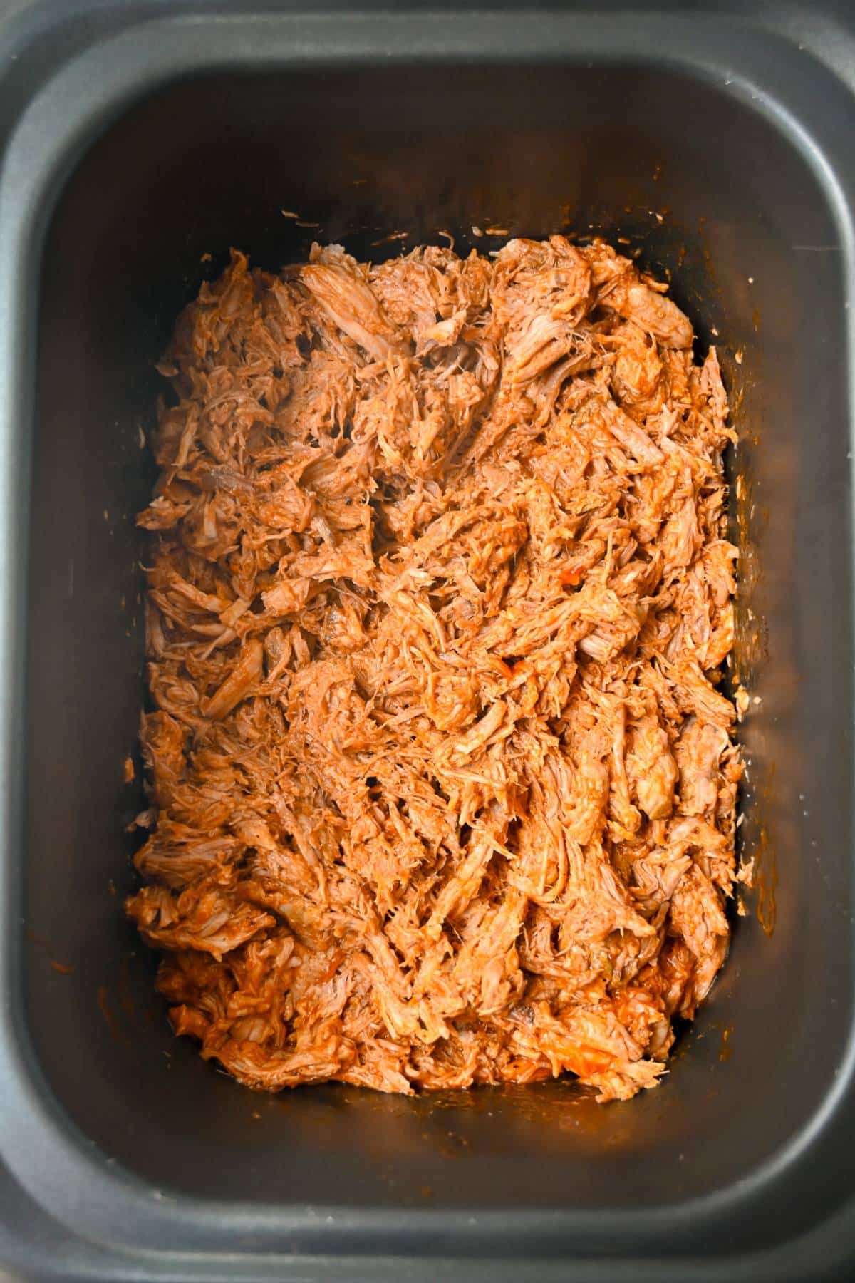 shredded cooked pork with bbq sauce in a slow cooker