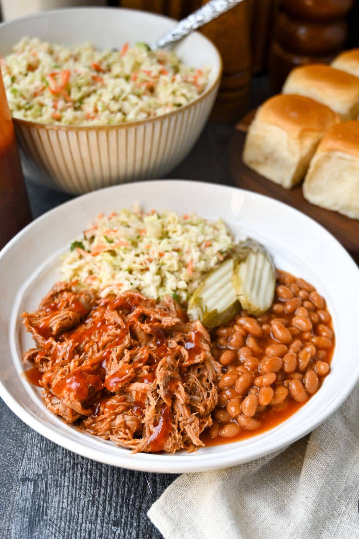 a bbq bowl, bowl of slaw, and platter of rolls