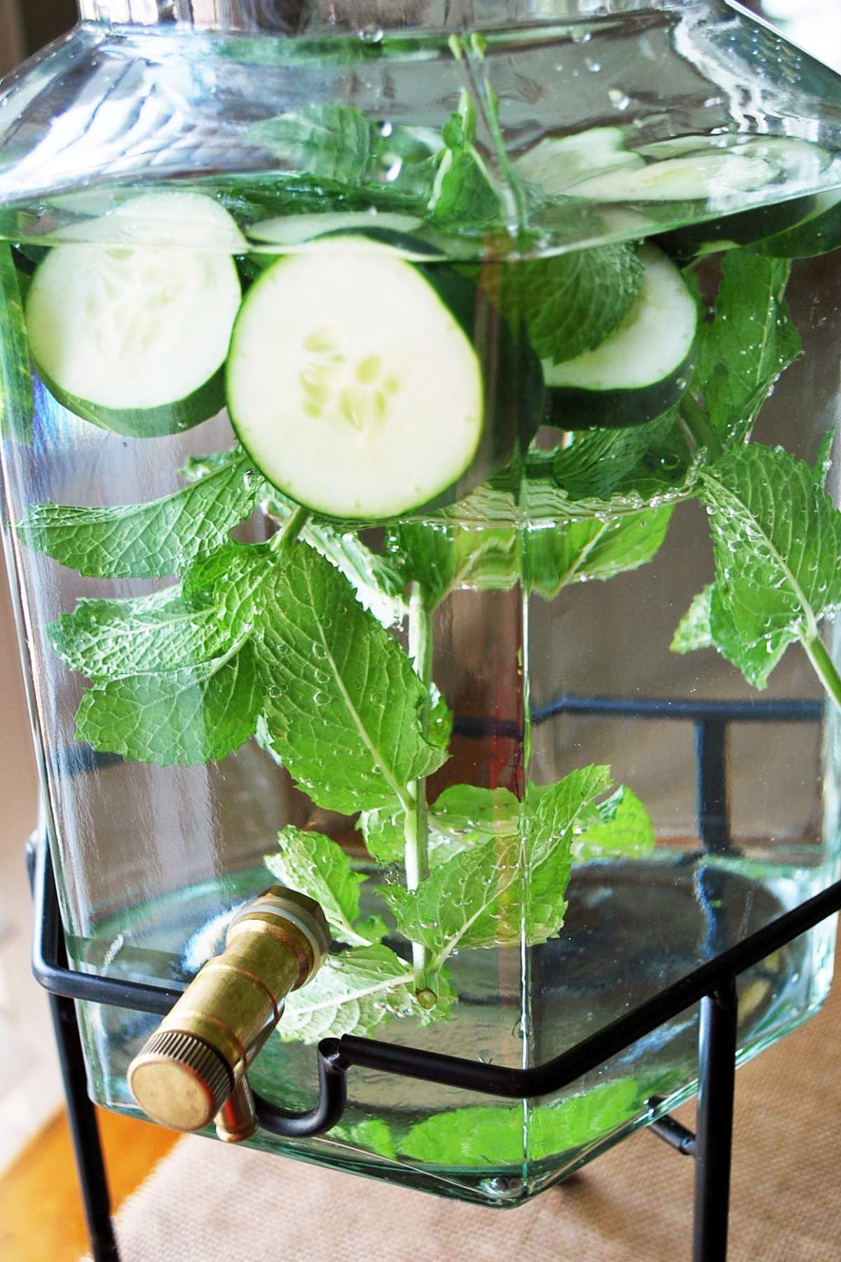 cucumbers and mint leaves in a drink dispenser with water