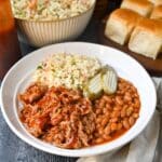 a BBQ bowl with pulled pork, beans, slaw, and pickles